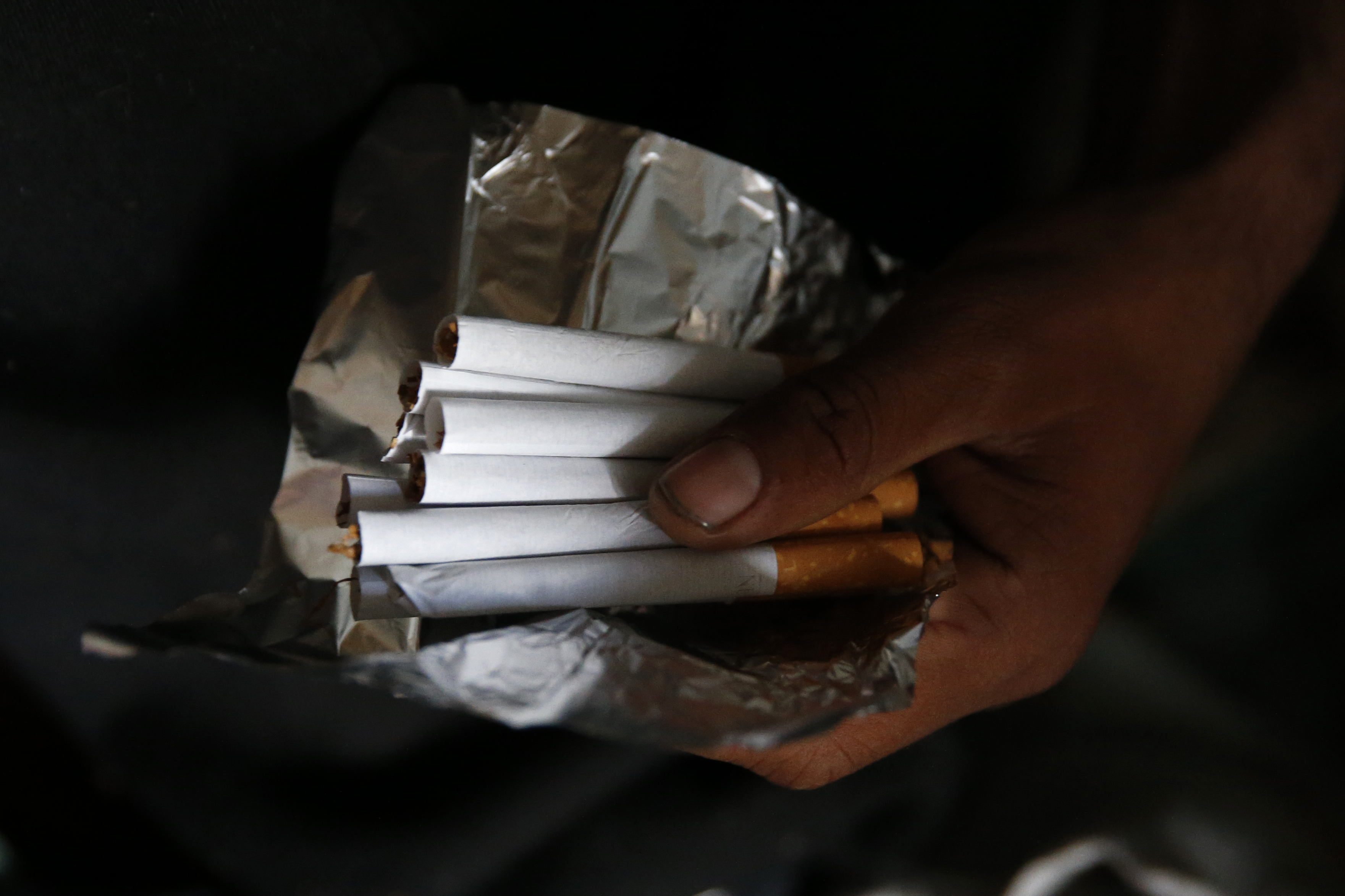 A migrant displays cigarettes which he rolled to be sold in a makeshift tent city located in a field in Calais