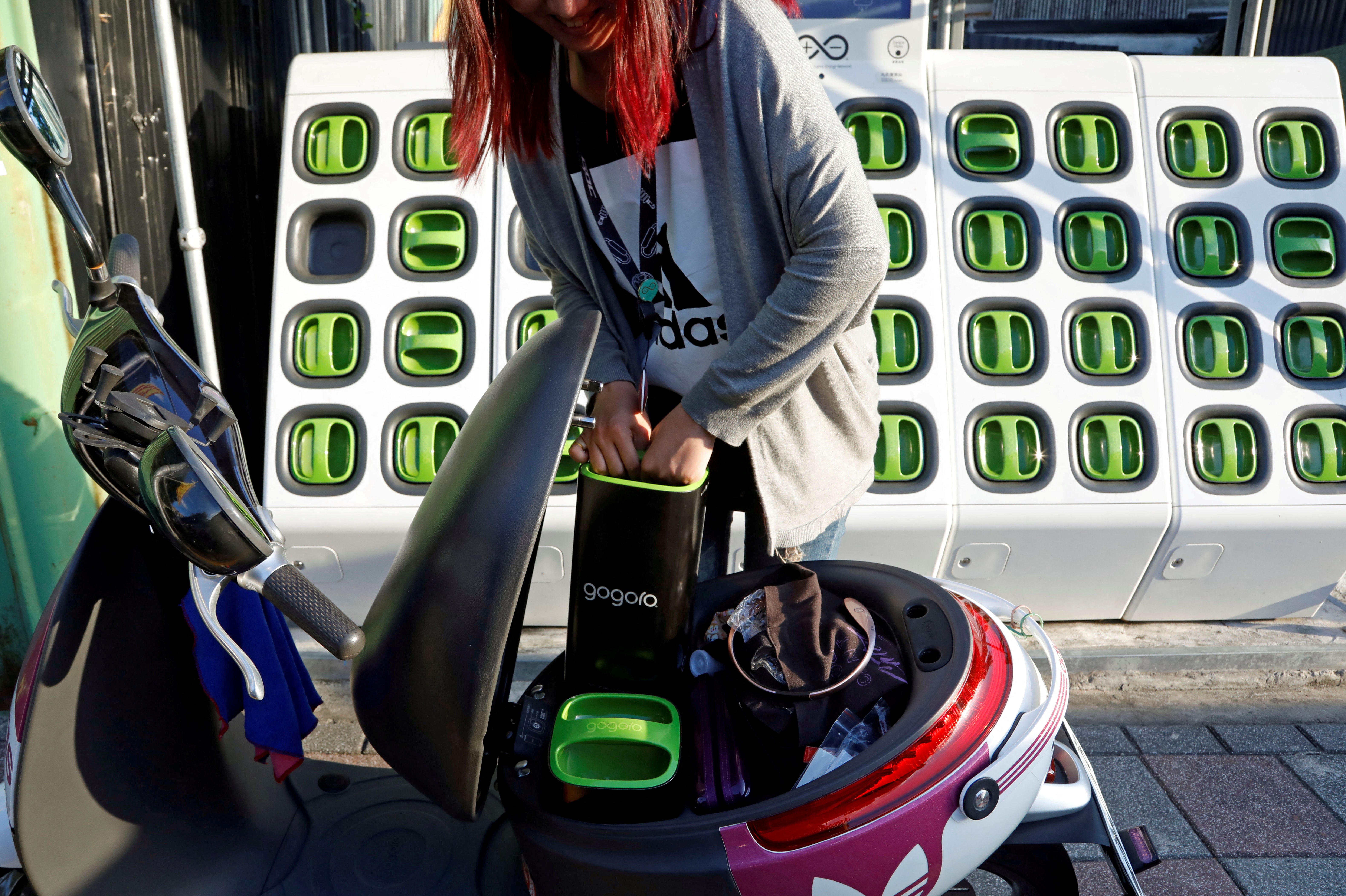 A woman charges battery of her electric scooter at the Gogoro's charging station in Taipei