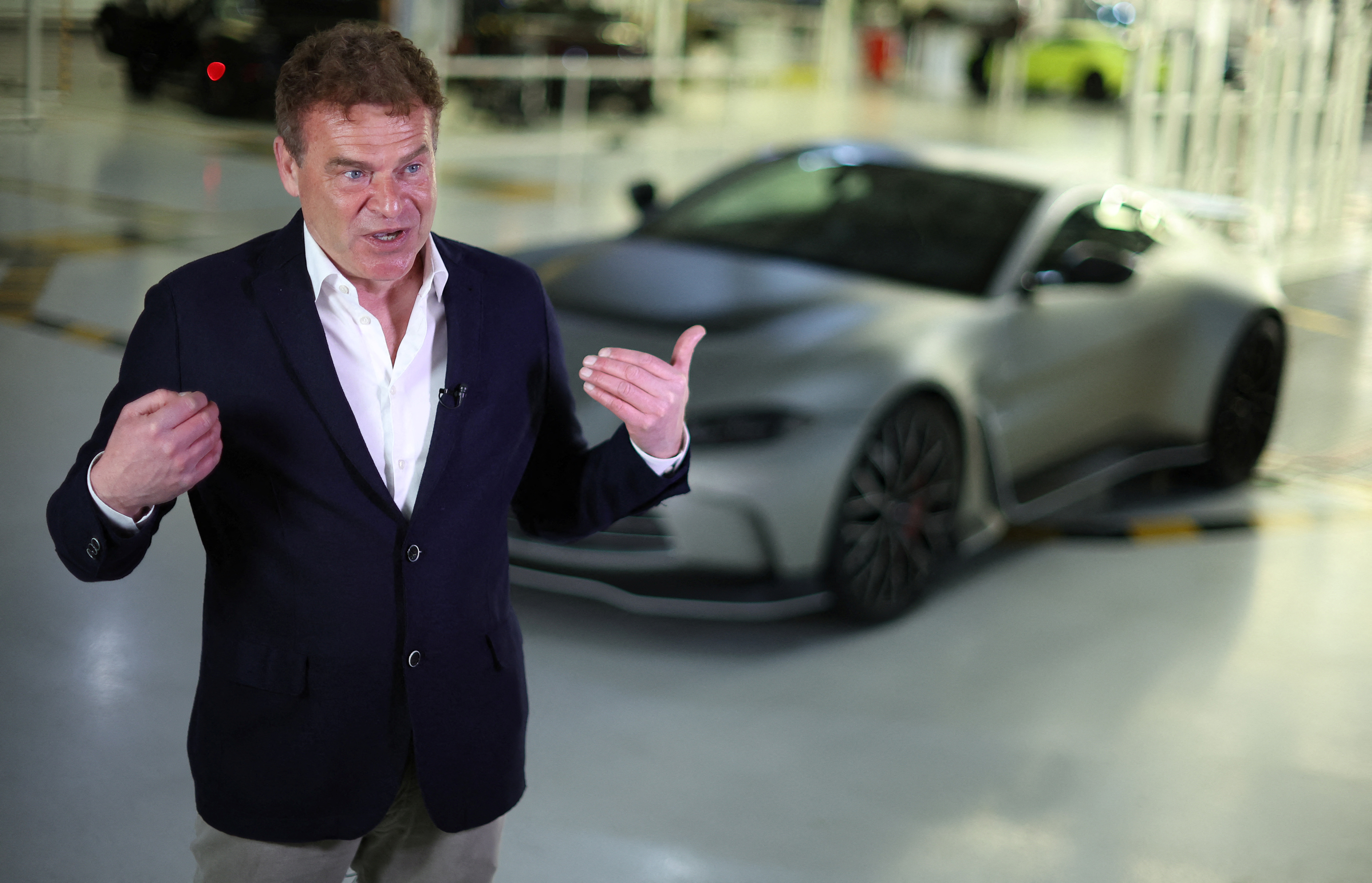 Aston Martin CEO Tobias Moers talks during a television interview in front of the new V12 Vantage car at the company’s factory in Gaydon
