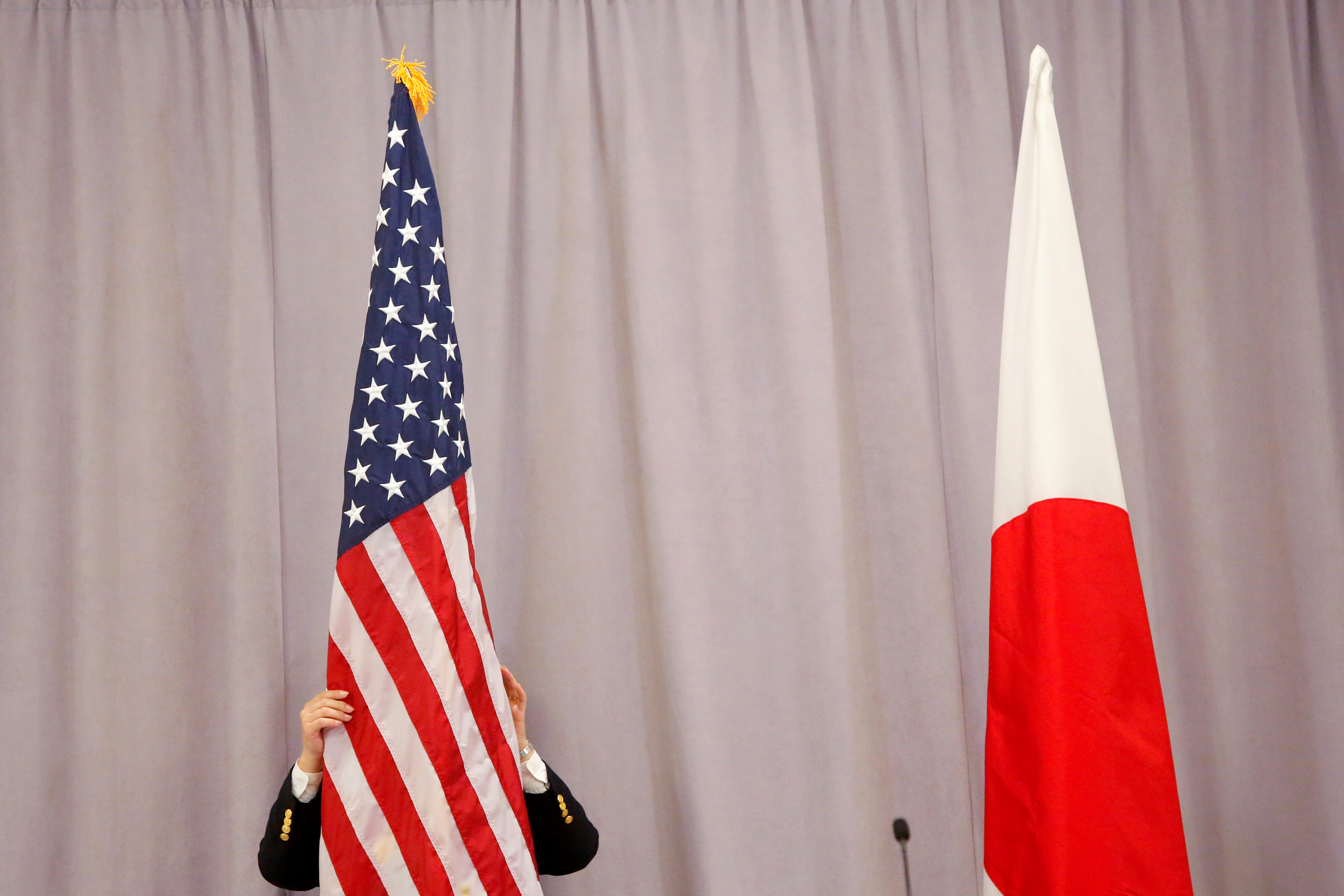 wA worker adjusts the U.S. flag before Japanese Prime Minister Shinzo Abe addresses media following a meeting with President-elect Donald Trump in Manhattan, New York, U.S.
