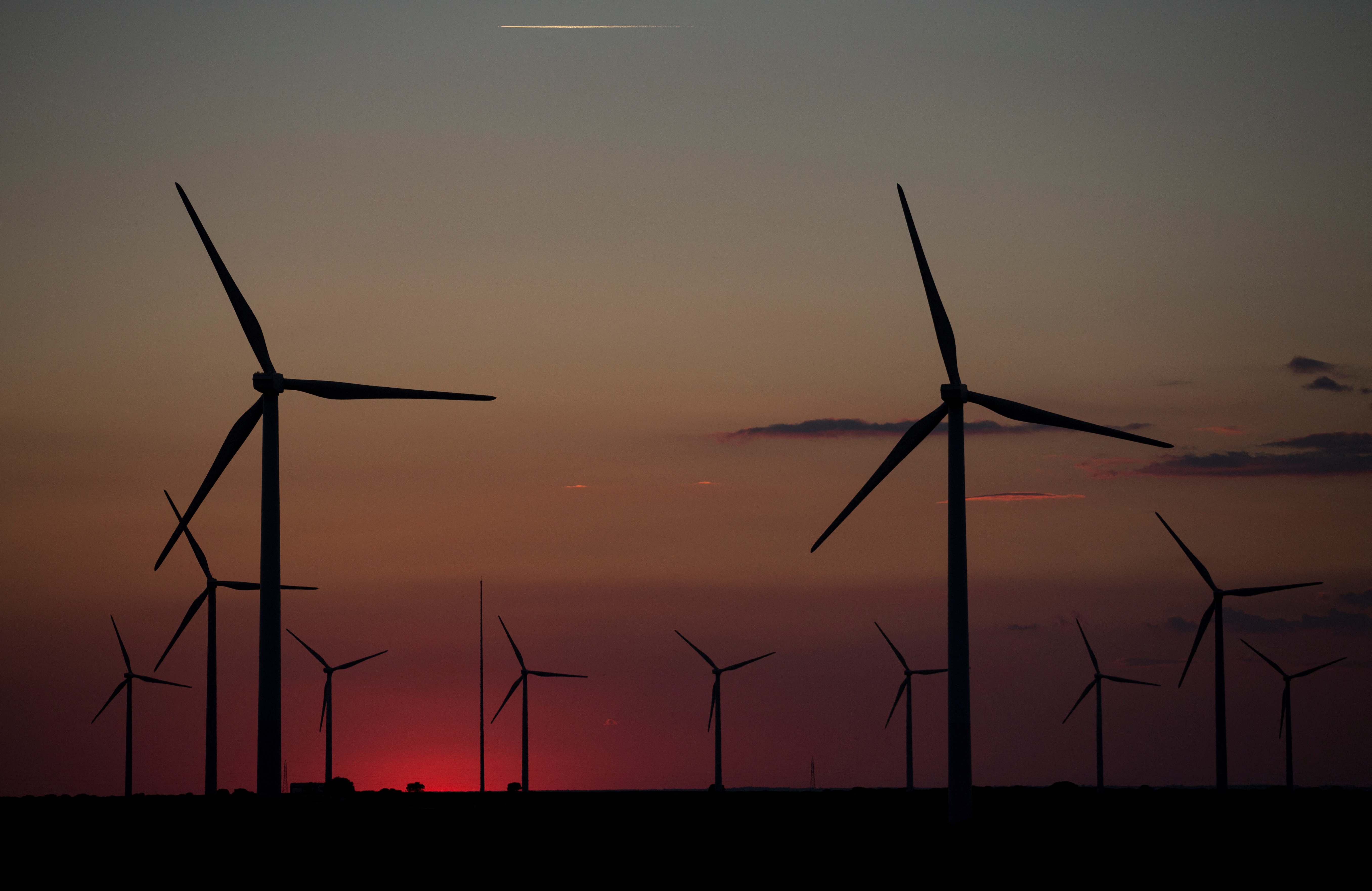 Wind turbines are seen at dusk in a field in Tebar