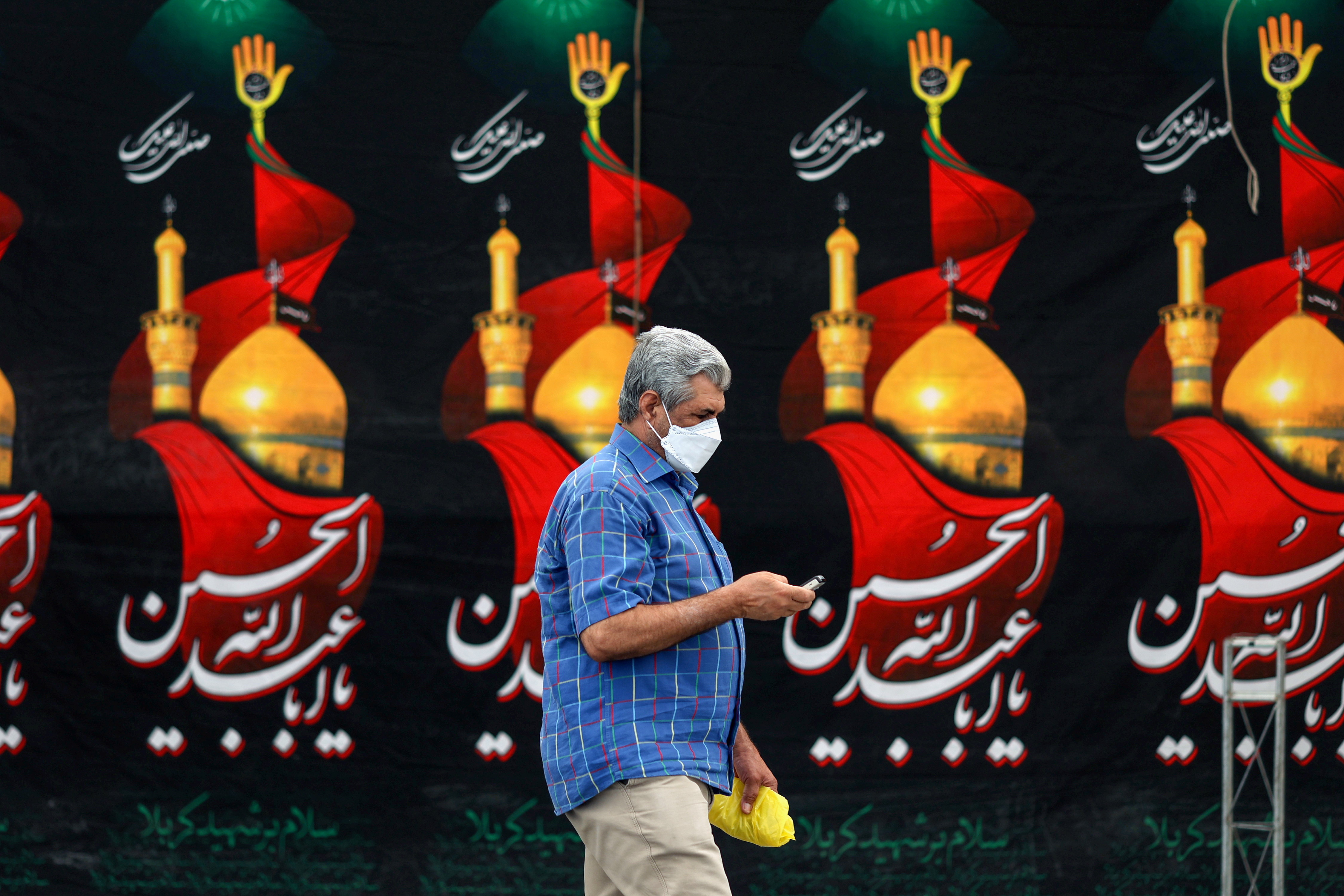 An Iranian man wearing a face mask walks down a street, as the coronavirus disease (COVID-19) cases spike, in Tehran