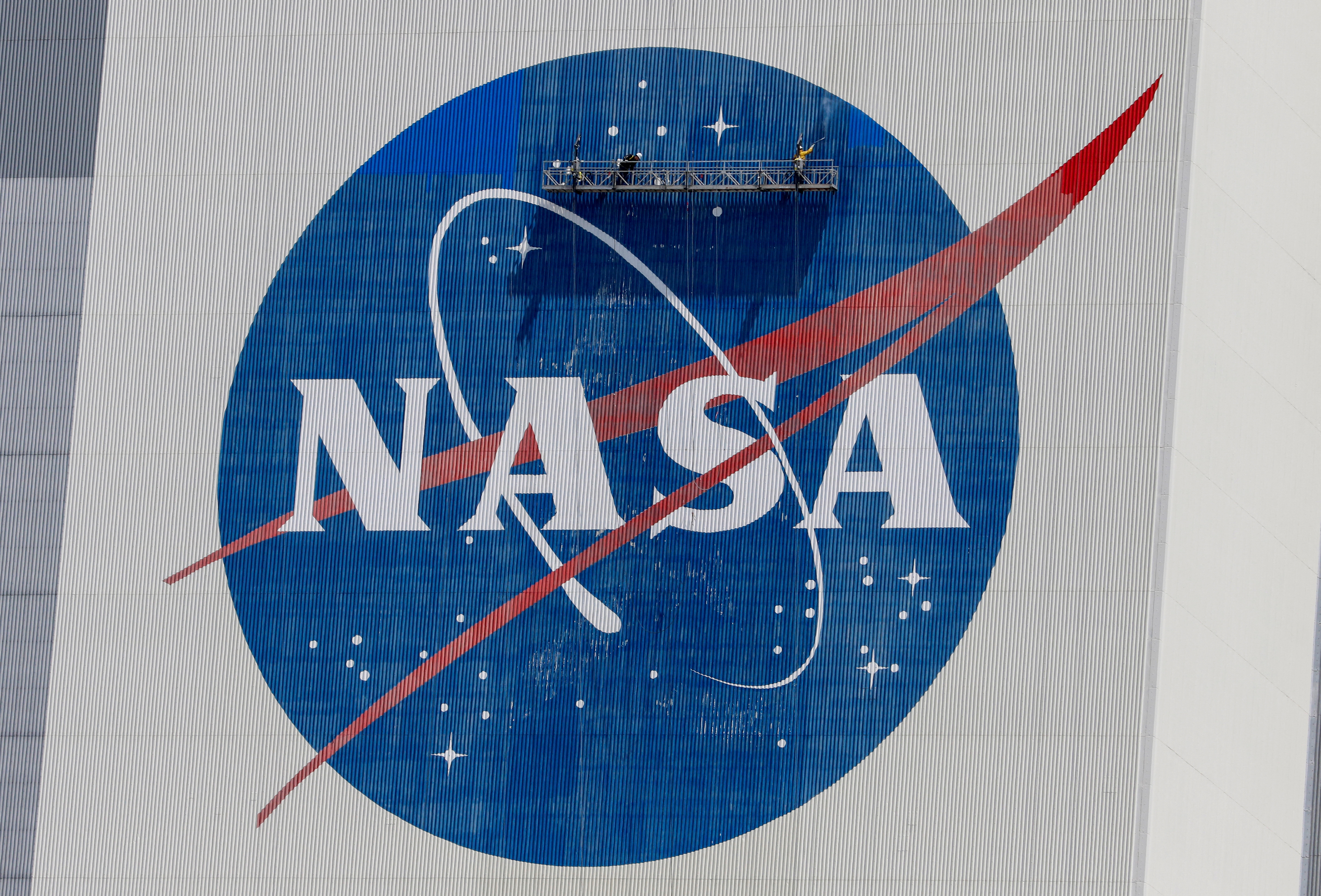 Workers pressure wash the logo of NASA on the Vehicle Assembly Building, in Cape Canaveral