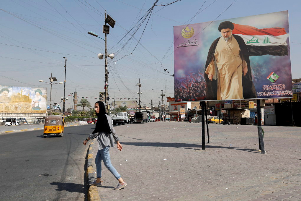 Girl walks near a poster of Iraqi Shi'ite cleric Moqtada al-Sadr in the Sadr City district of Baghdad
