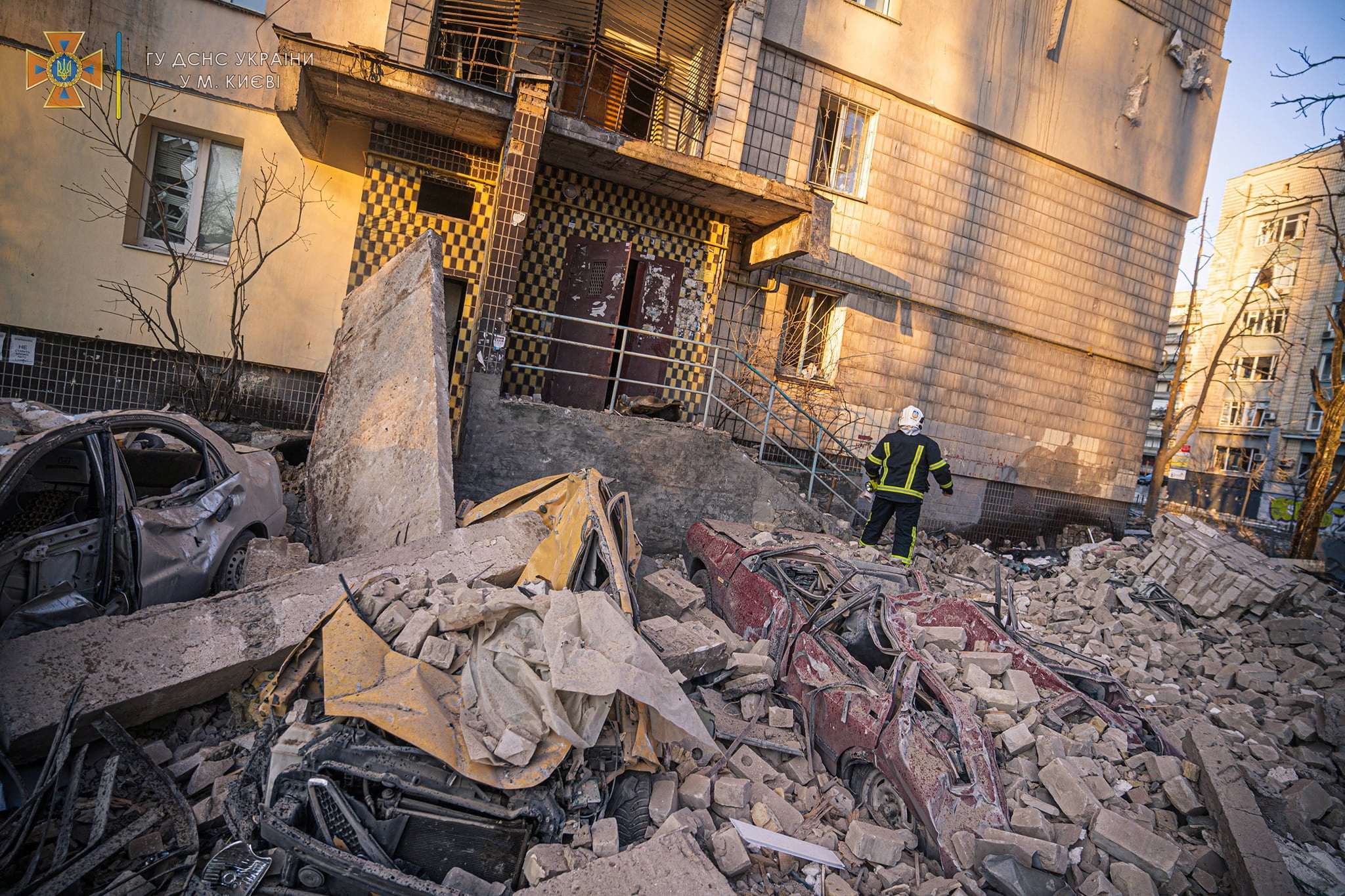A rescuer works next to a residential building damaged by shelling in Kyiv