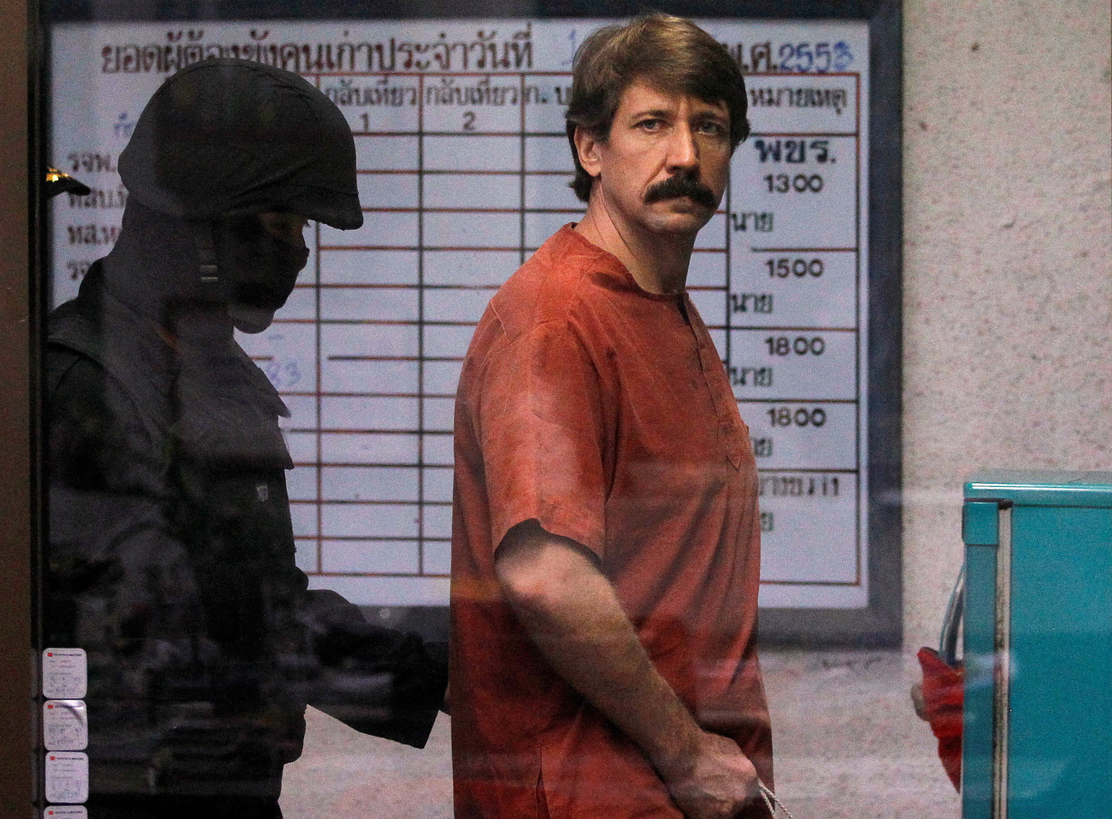 Bout from Russia is escorted by a member of the special police unit as he arrives at a criminal court in Bangkok