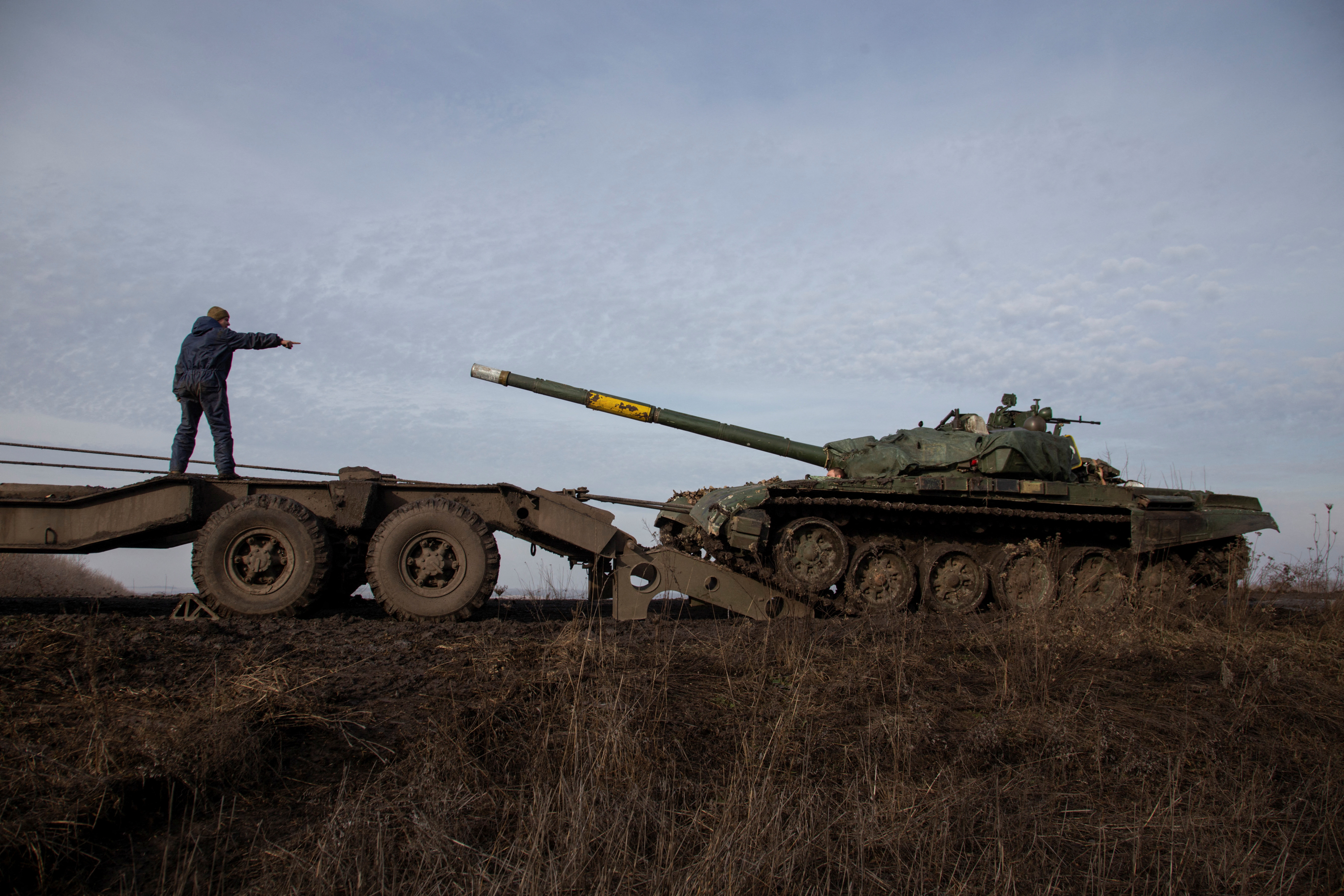 Ukrainian serviceman gestures during pulling a broken tank to a truck near the frontline town of Bakhmut