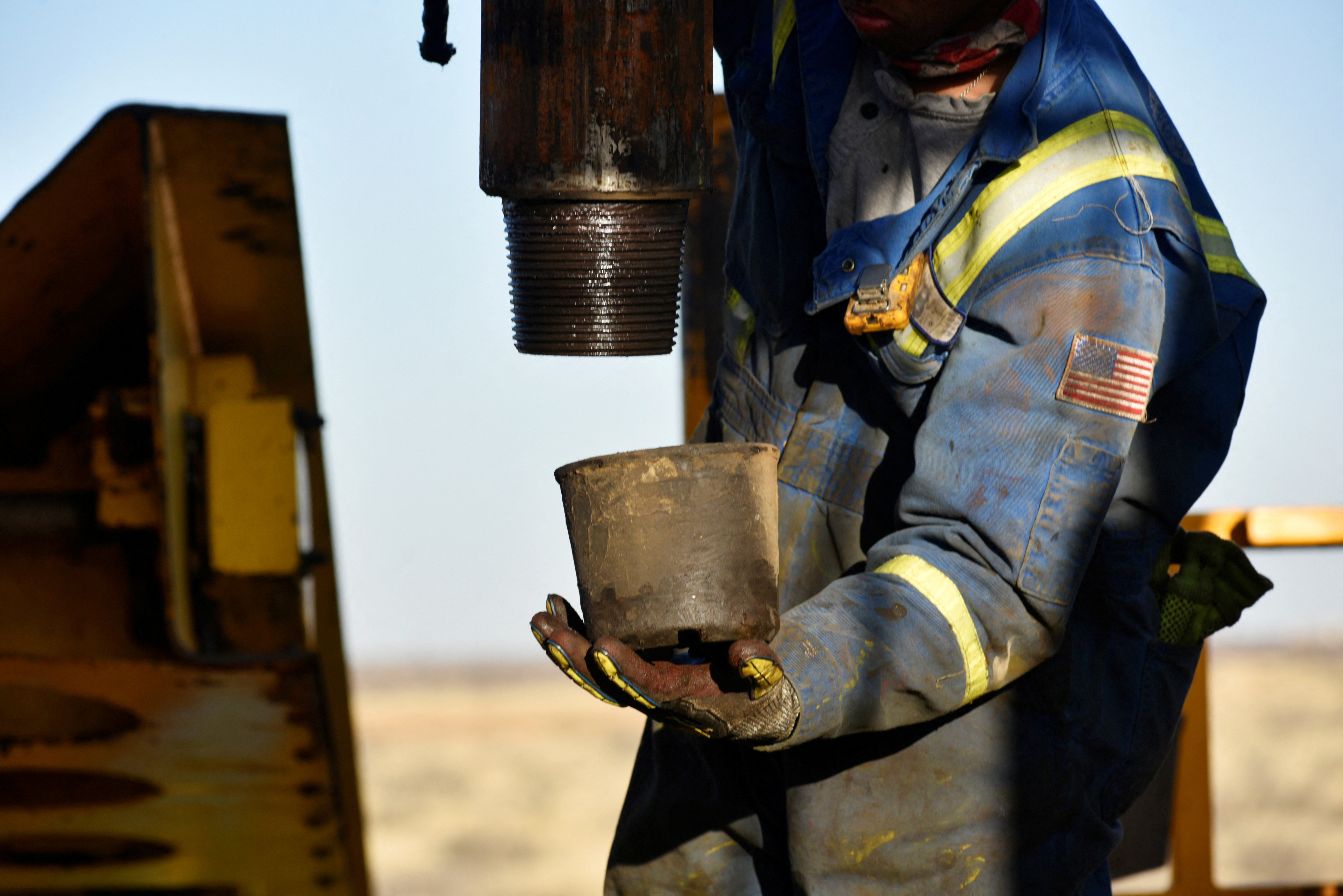 An oil worker removes a thread cap from a piece of drill pipe on a drilling lease owned by Elevation Resources near Midland