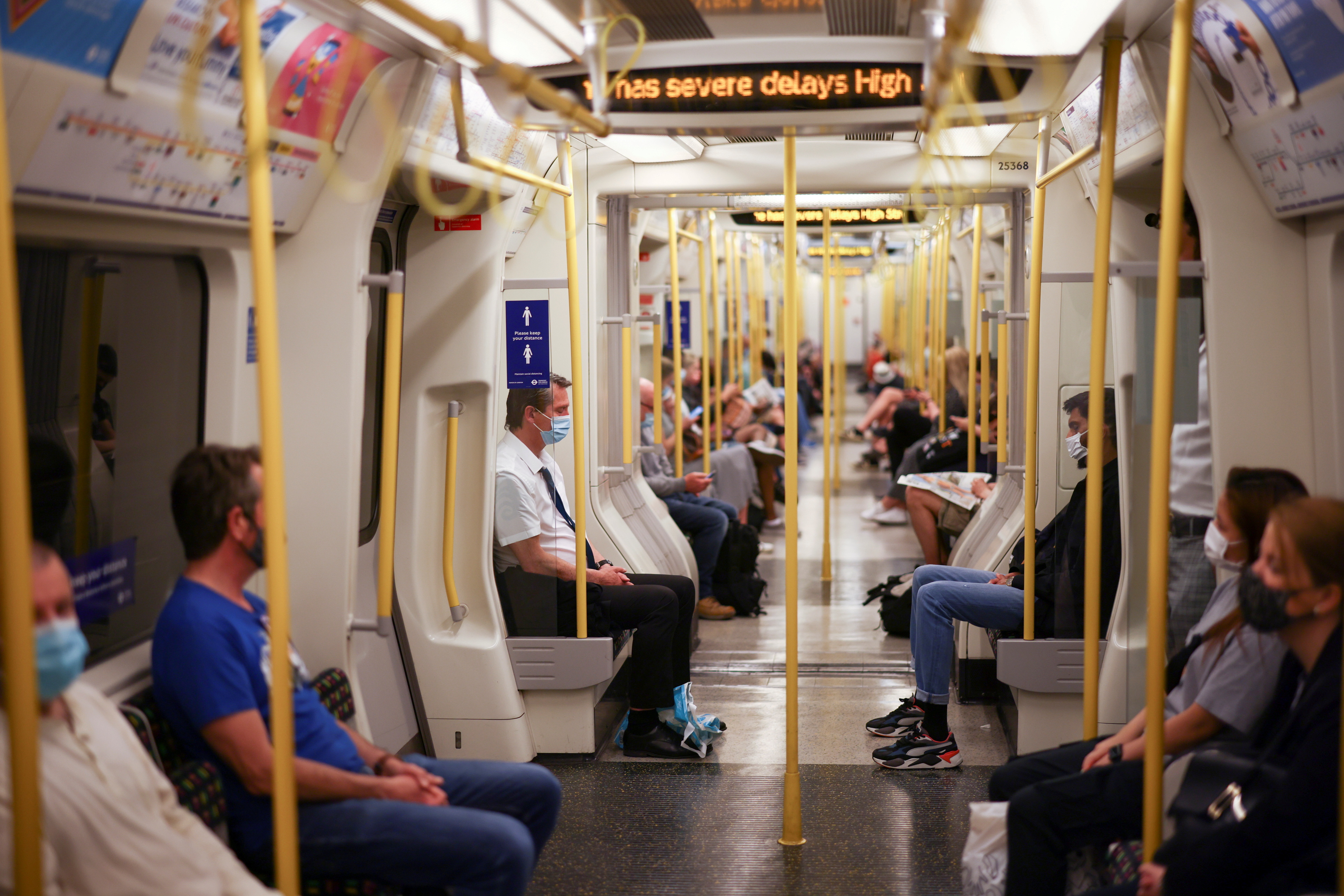 People ride aboard a London Underground train, in central London