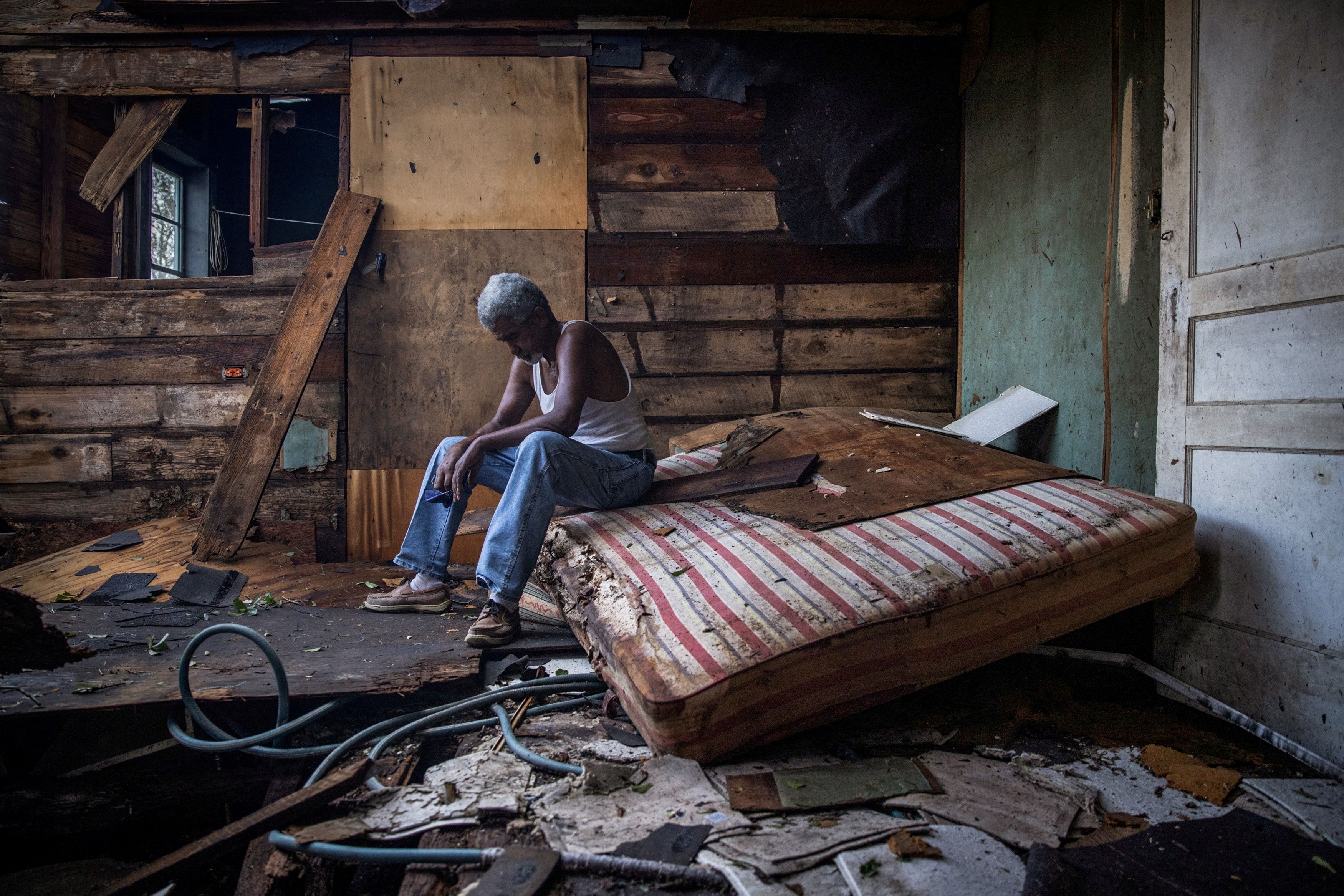 Theophilus Charles, 70, sits inside his house which was heavily damaged by Hurricane Ida in Houma