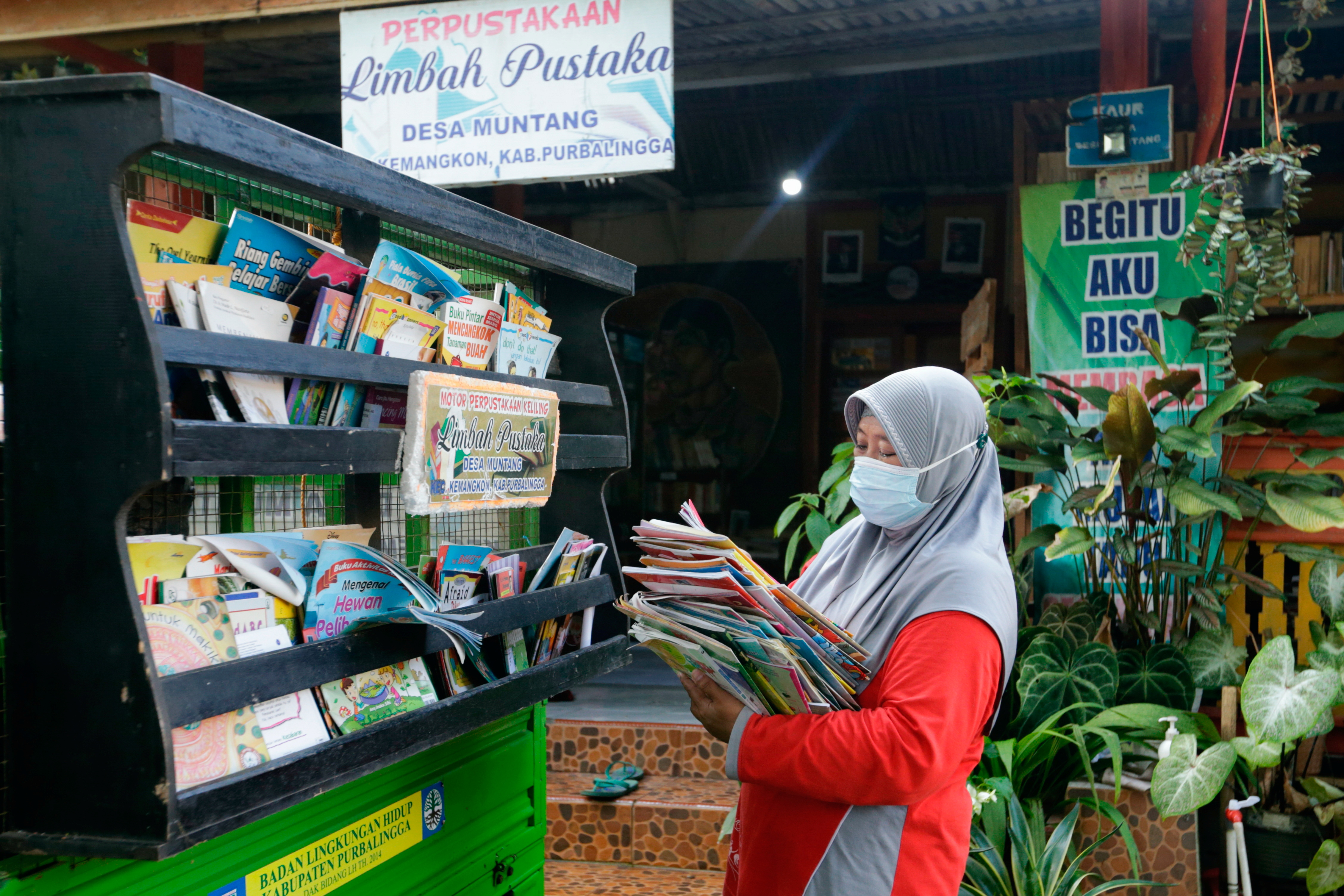 Founder of the waste library (Limbah Pustaka), Raden Roro Hendarti arranges books on a three-wheeler vehicle at the library in Muntang village