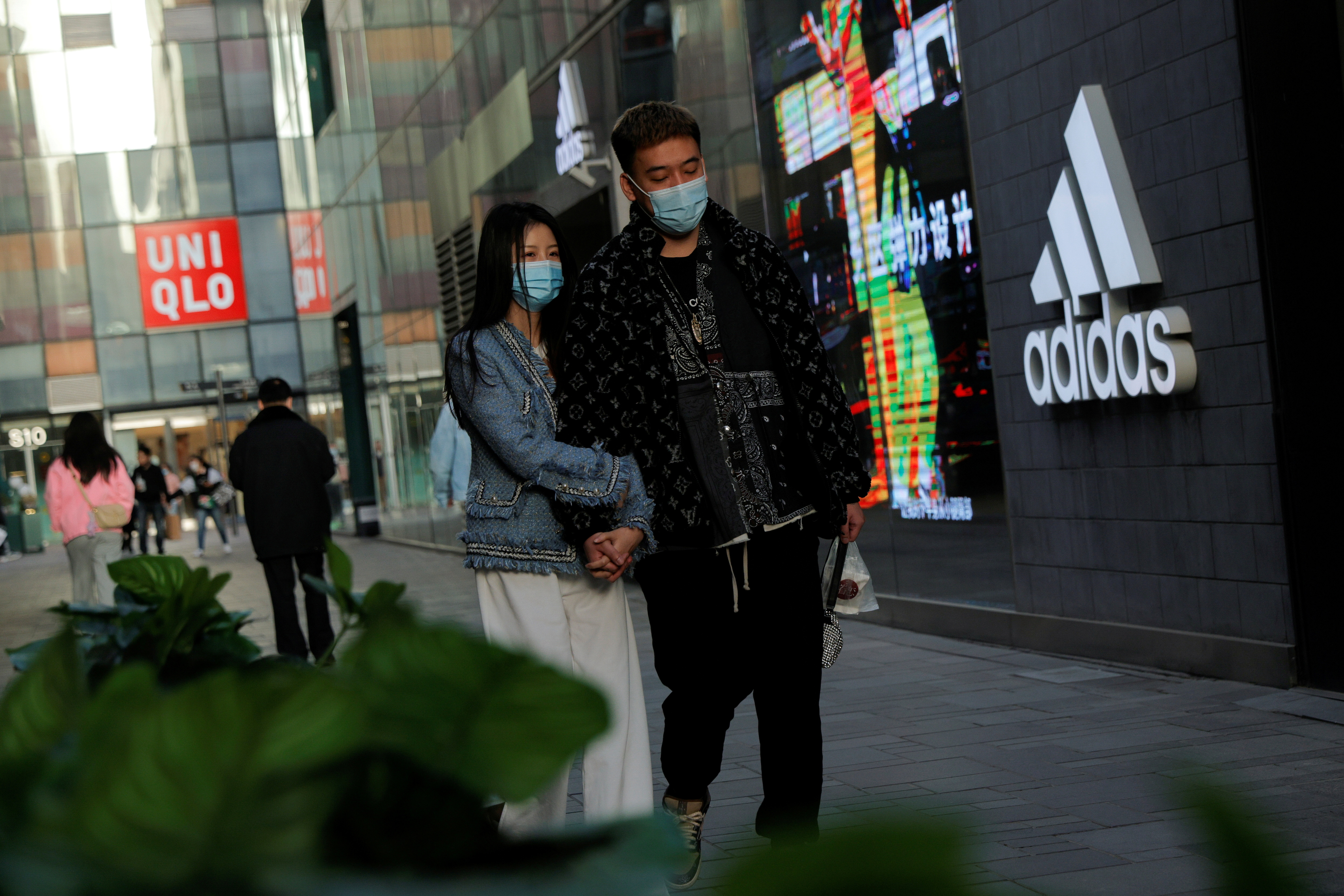 People walk past an Adidas store in a shopping area in Beijing, China, March 28, 2021. REUTERS/Thomas Peter/File Photo