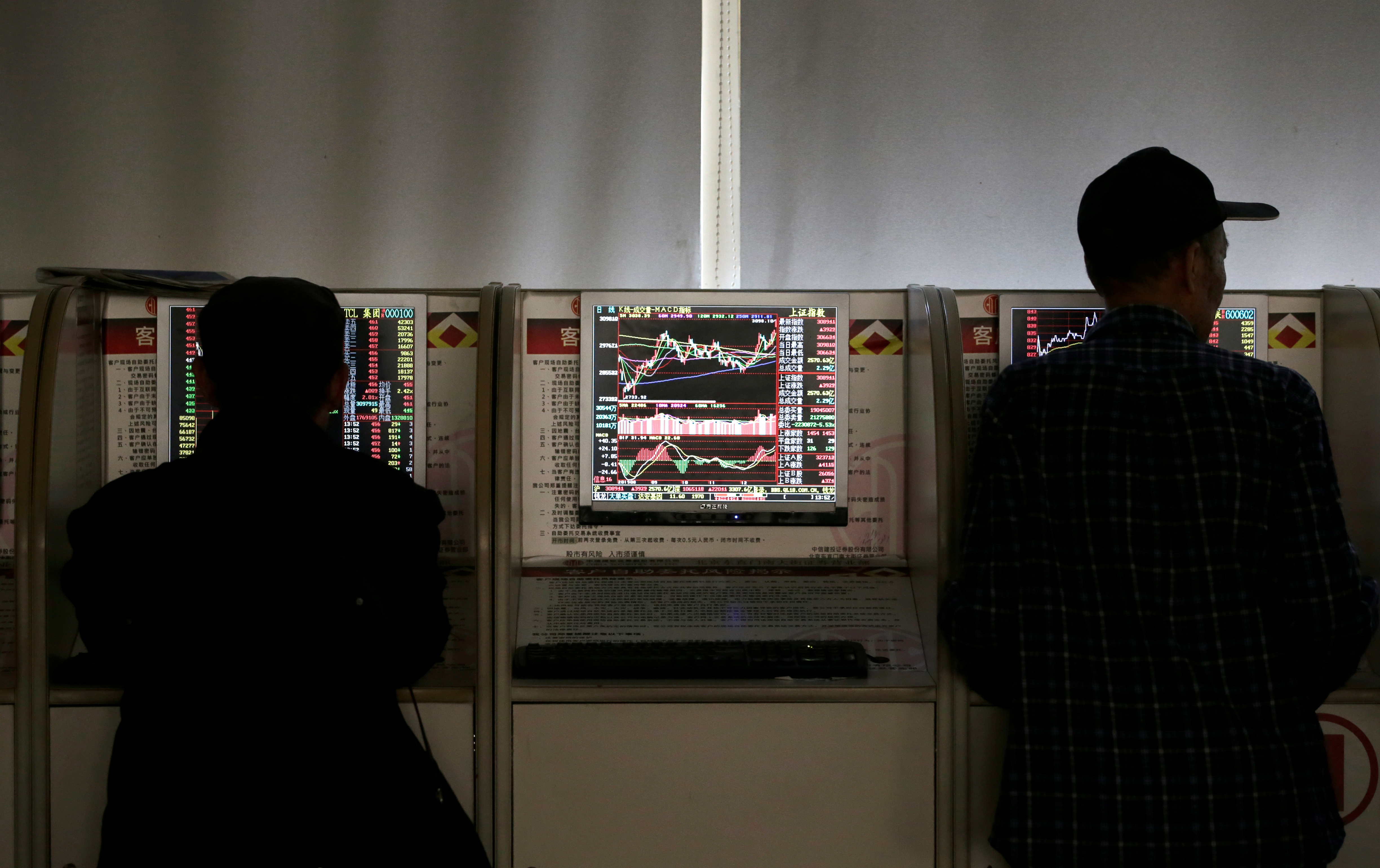Investors check share prices at a brokerage office in Beijing