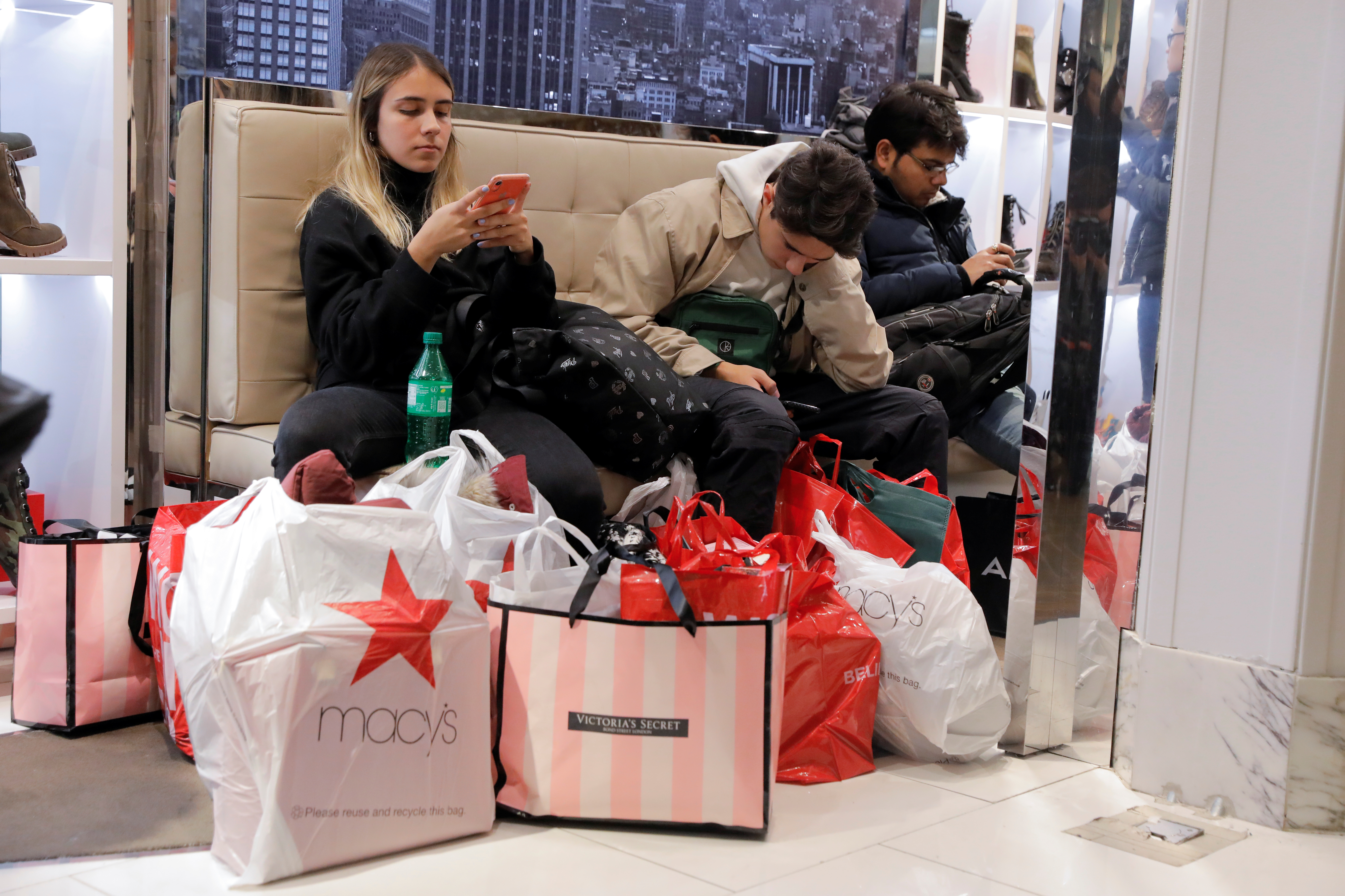 People rest with shopping bags at Macy's Herald Square during early opening for the Black Friday sales in Manhattan, New York City