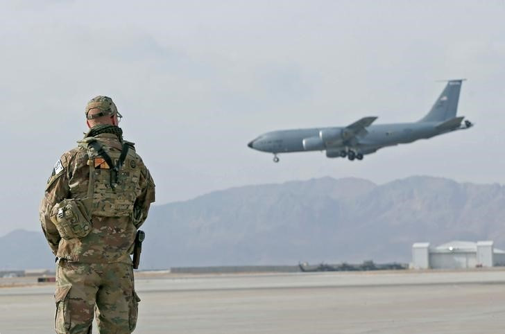 U.S. service member stands guard as an U.S. military transport plane lands at the Kandahar air base