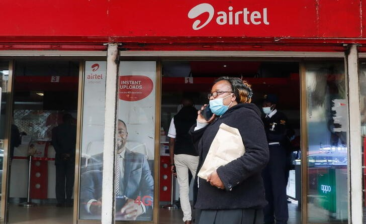 A woman speaks on her cellphone as she walks past a mobile phone service centre operated by Kenyan's telecom operator Airtel Kenya in downtown Nairobi