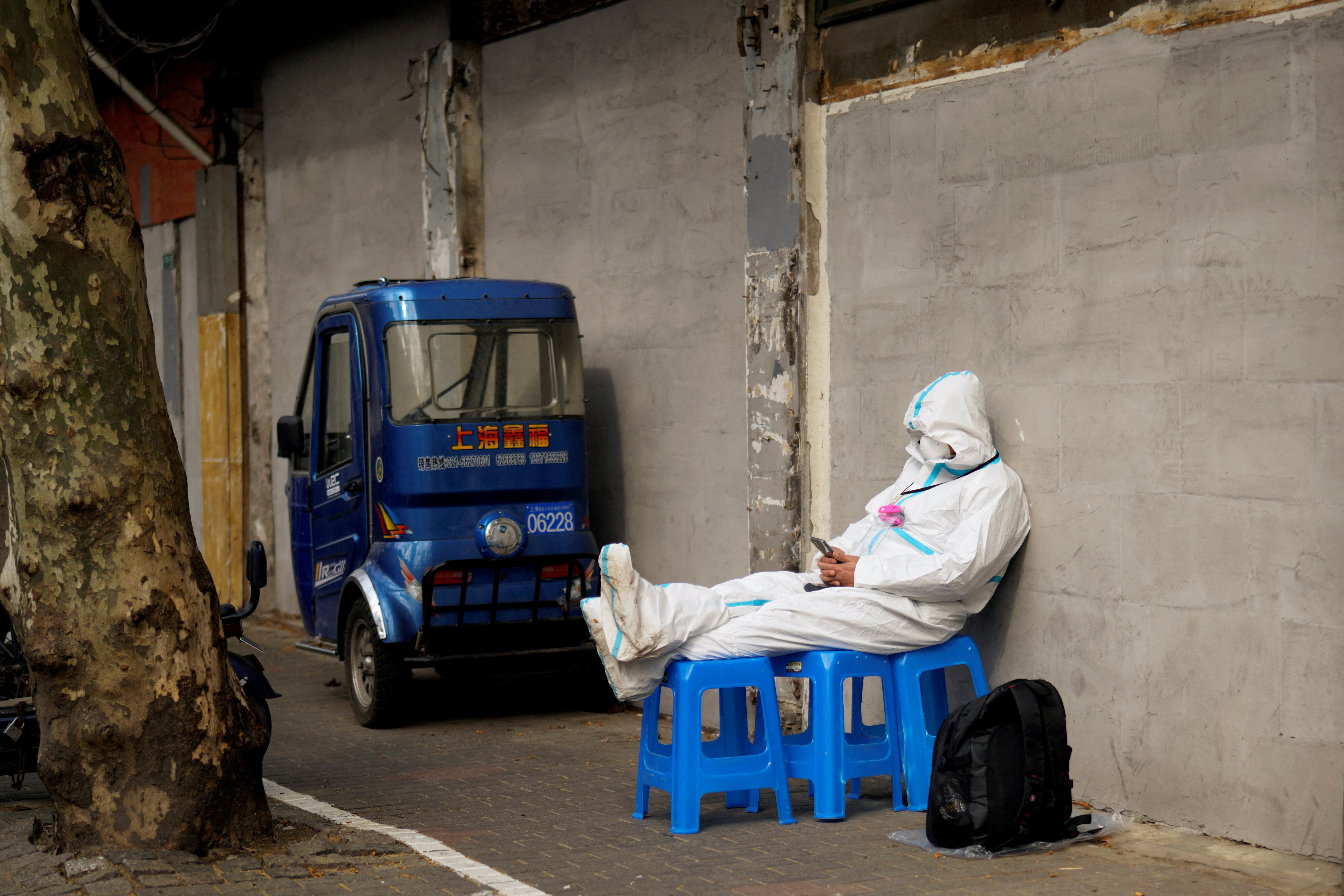 A worker in a protective suit sits on plastic stools following the coronavirus disease (COVID-19) outbreak in Shanghai, China March 30, 2022.