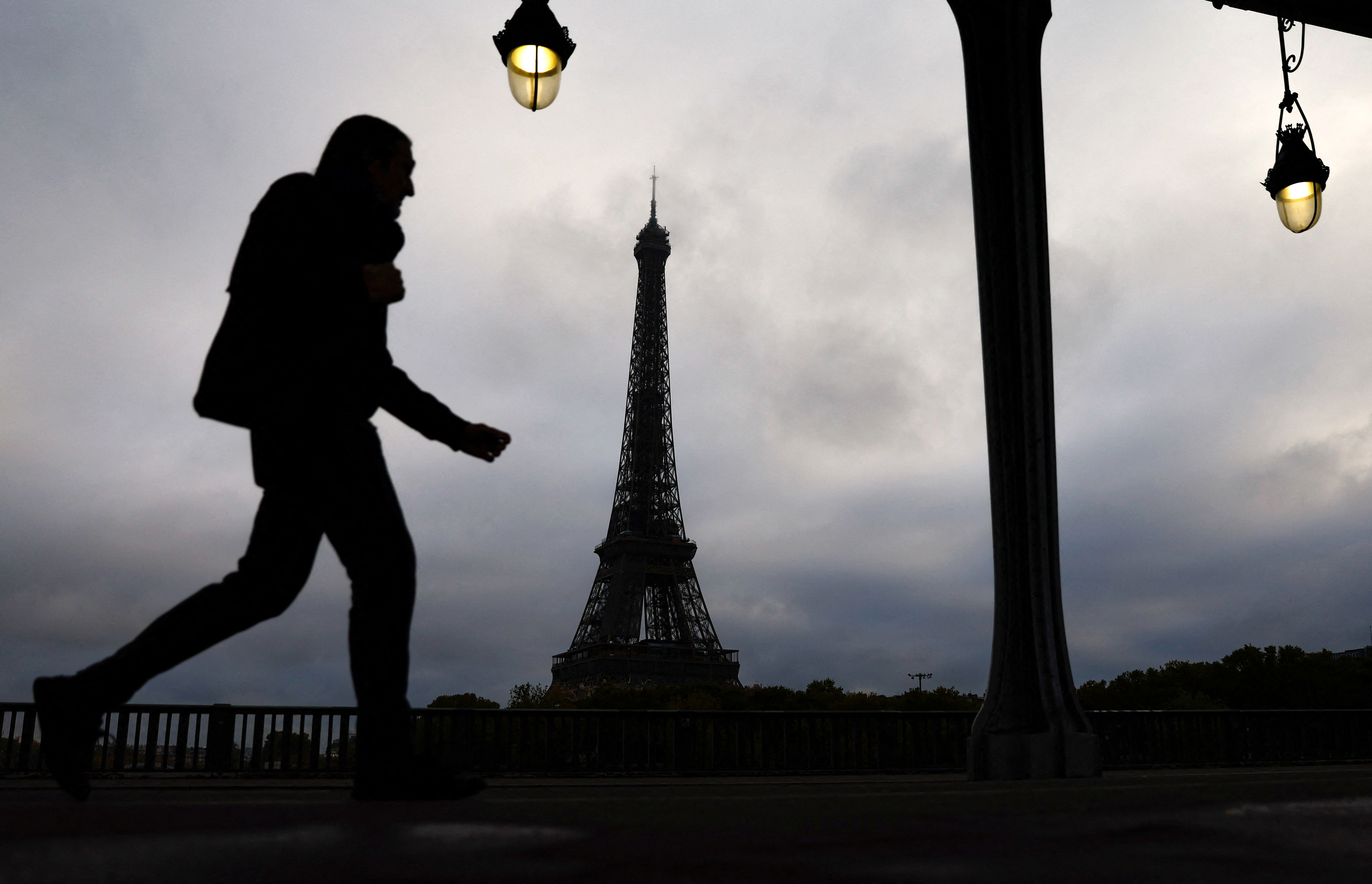 A man walks on the Pont de Bir-Hakeim bridge near the Eiffel Tower in Paris
