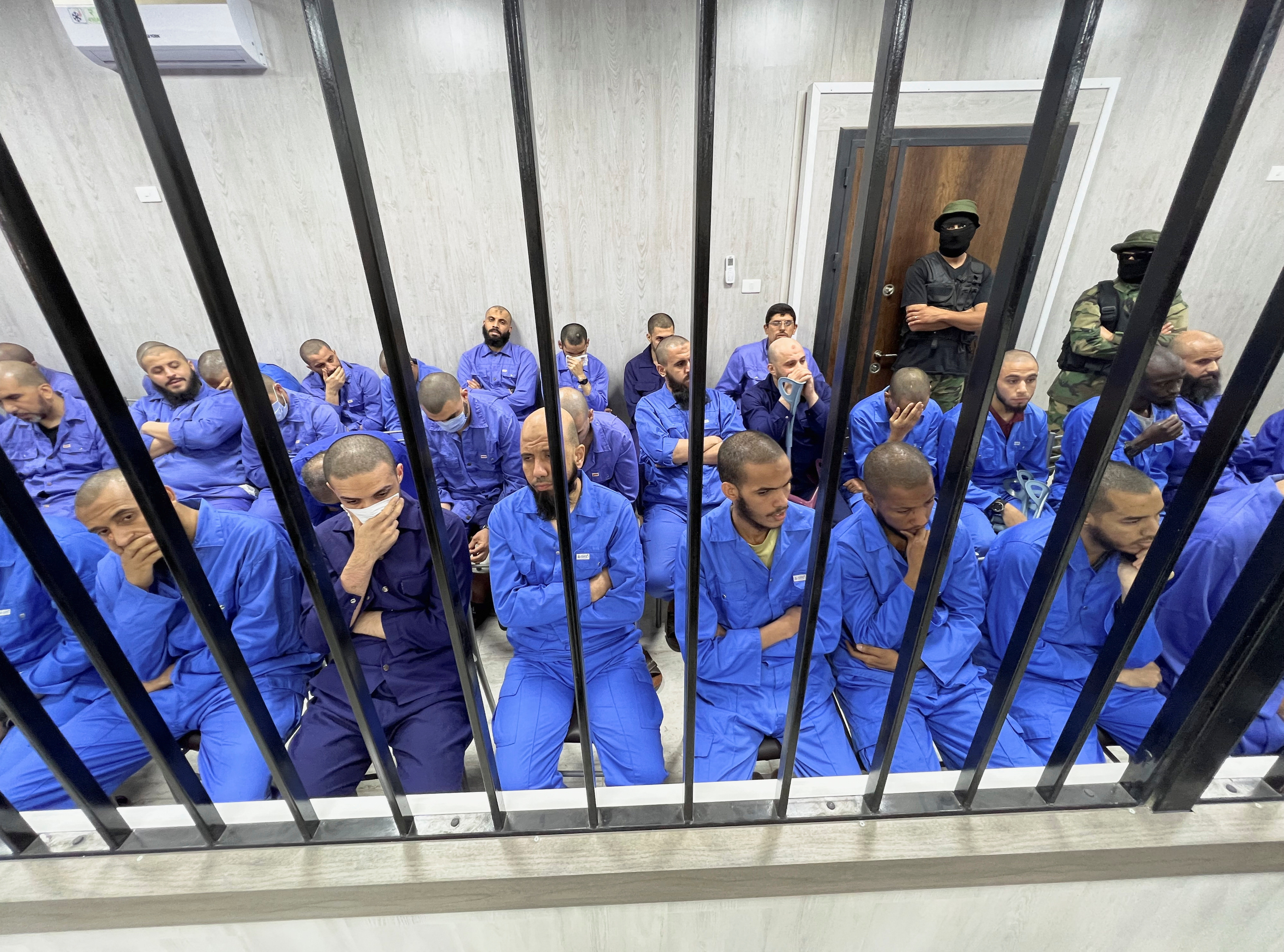 Suspects sit behind bars during a judgment sentence against 56 defendants accused of joining Islamic State group in the court in Misrata