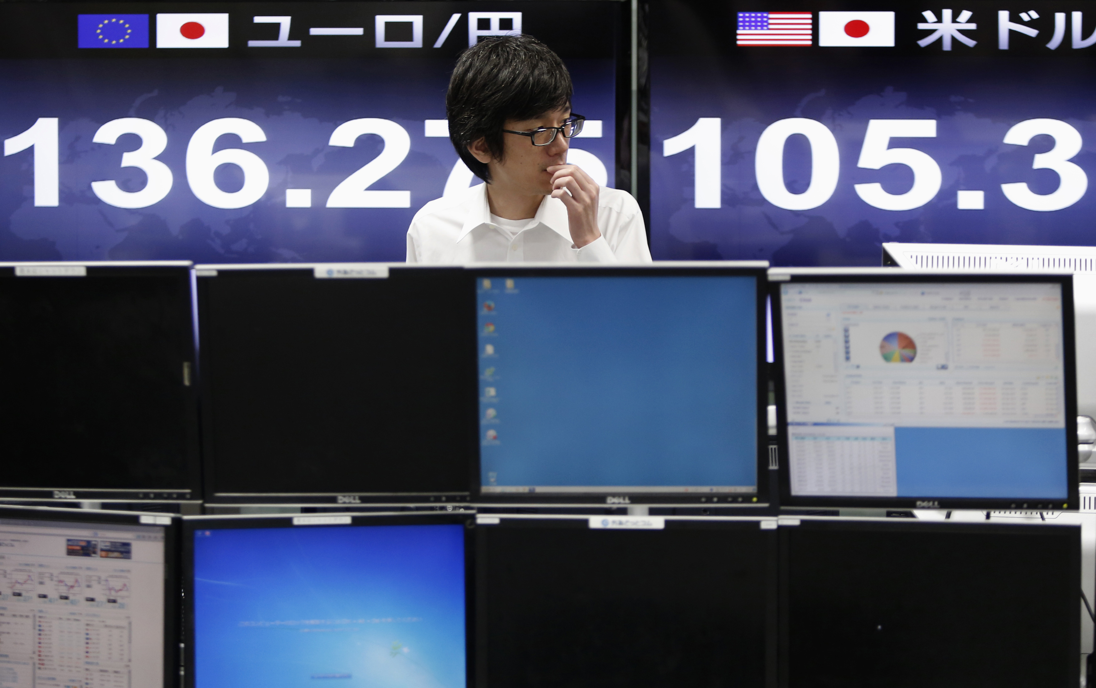 An employee of a foreign exchange trading company stands in front of the monitors displaying exchange rates in Tokyo