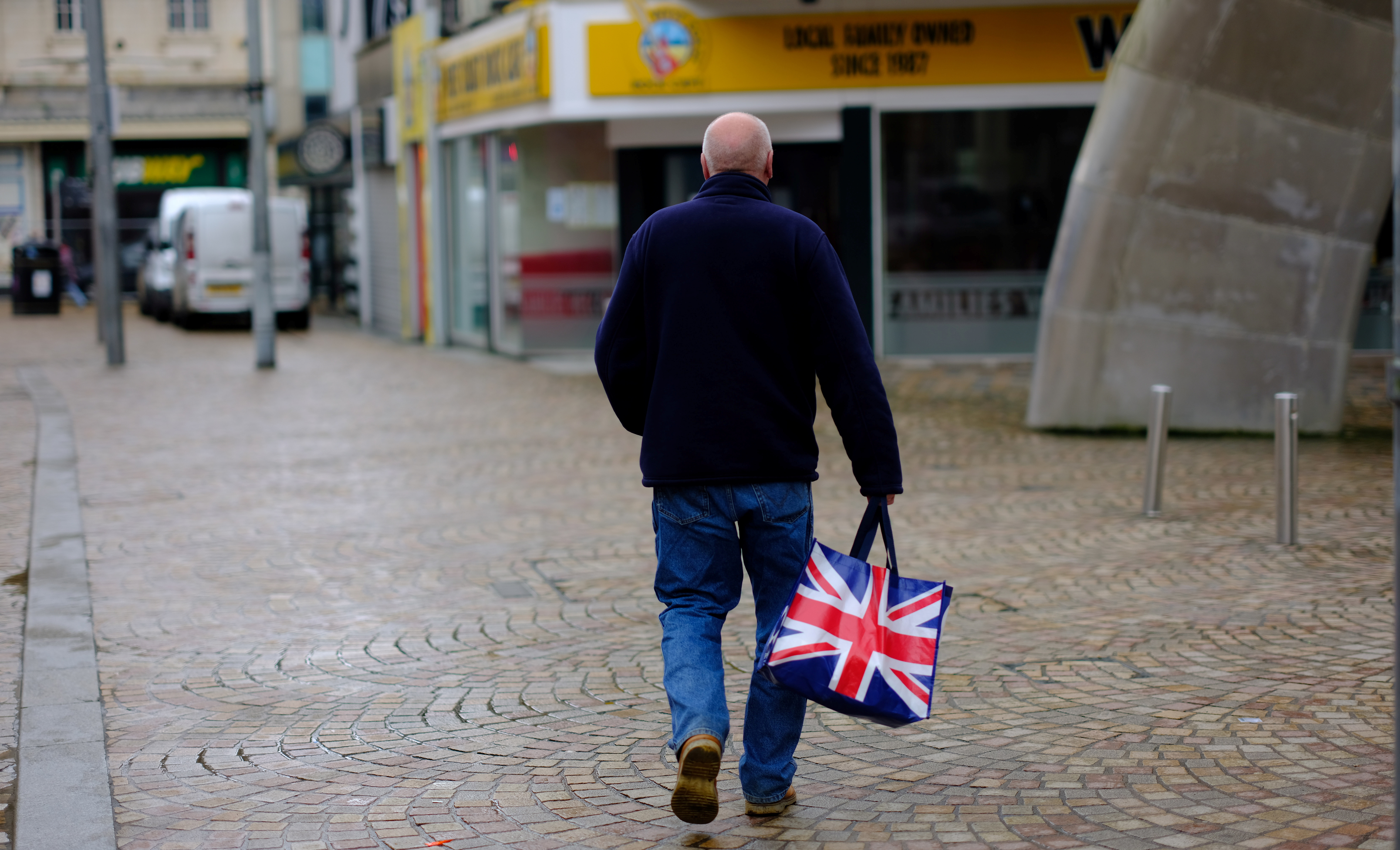A man carries a Union Jack themed shopping bag as he walks along an empty shopping street in Blackpool