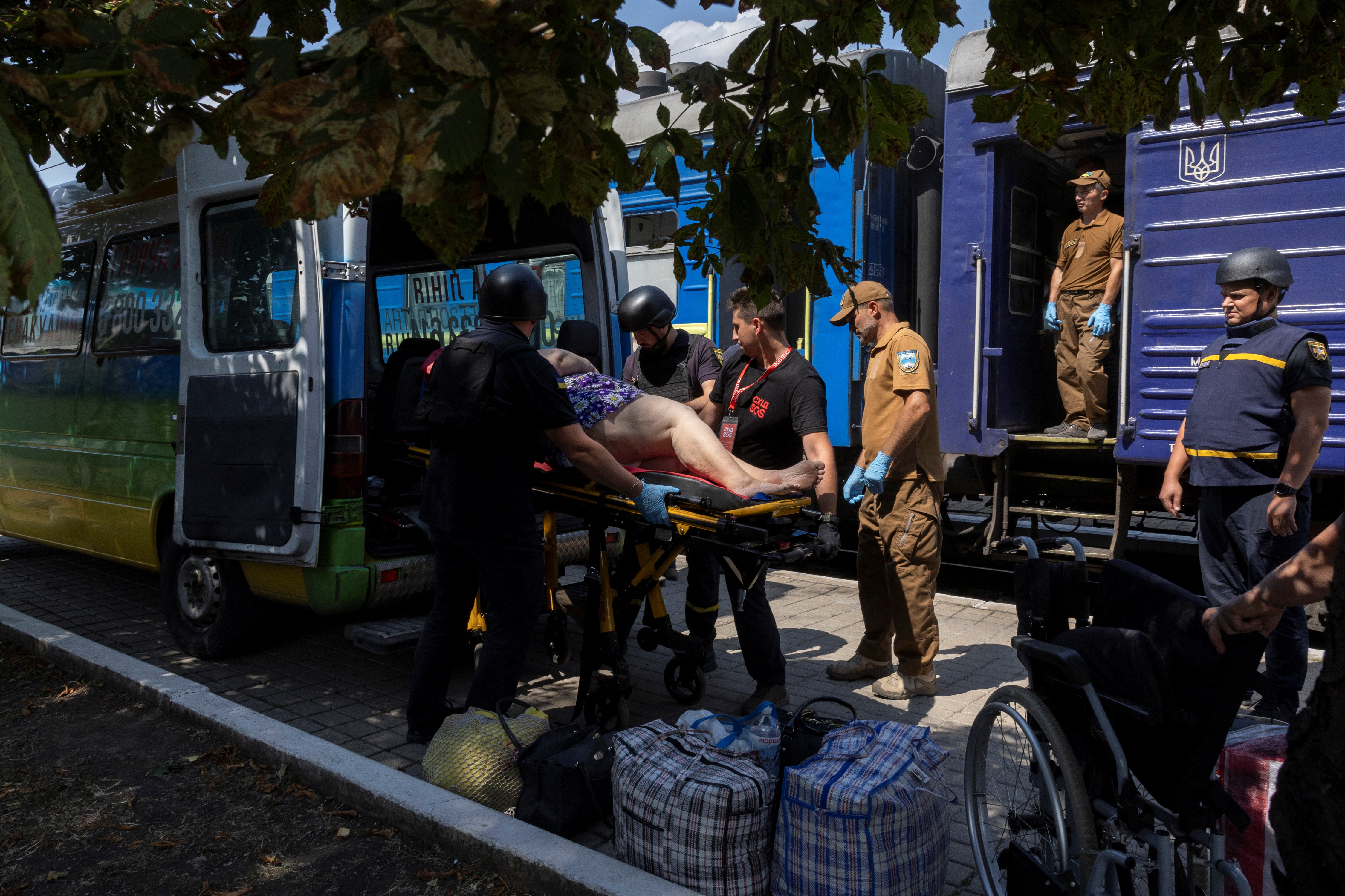 Volunteers of East SOS evacuate a woman, as Russian forces advance across the frontlines in the Donetsk region, at the train station in Pokrovsk