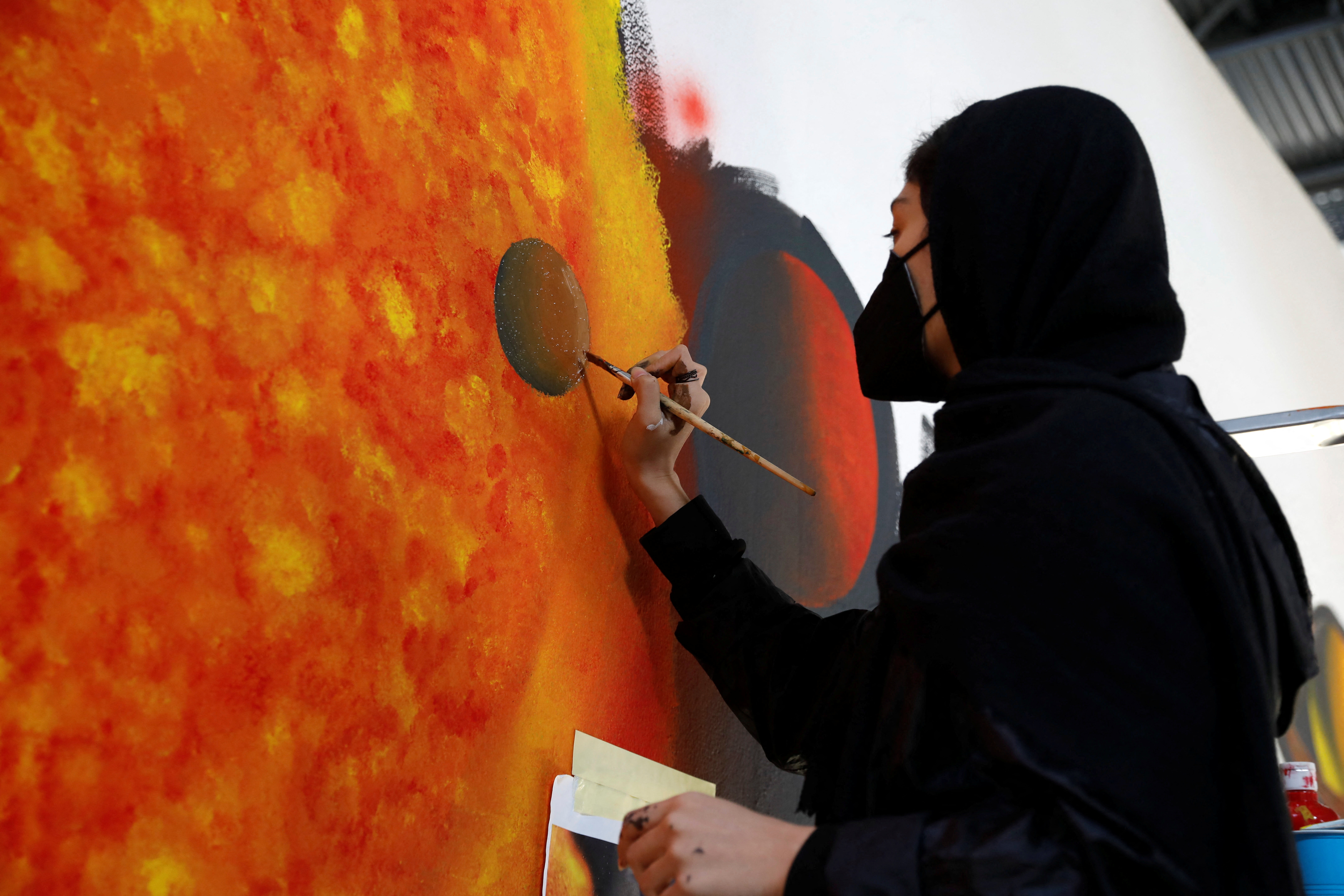 Roya Rasuli, an 18-year-old Afghan migrant artist, draws on a wall at a camp for refugees and migrants, in Thiva