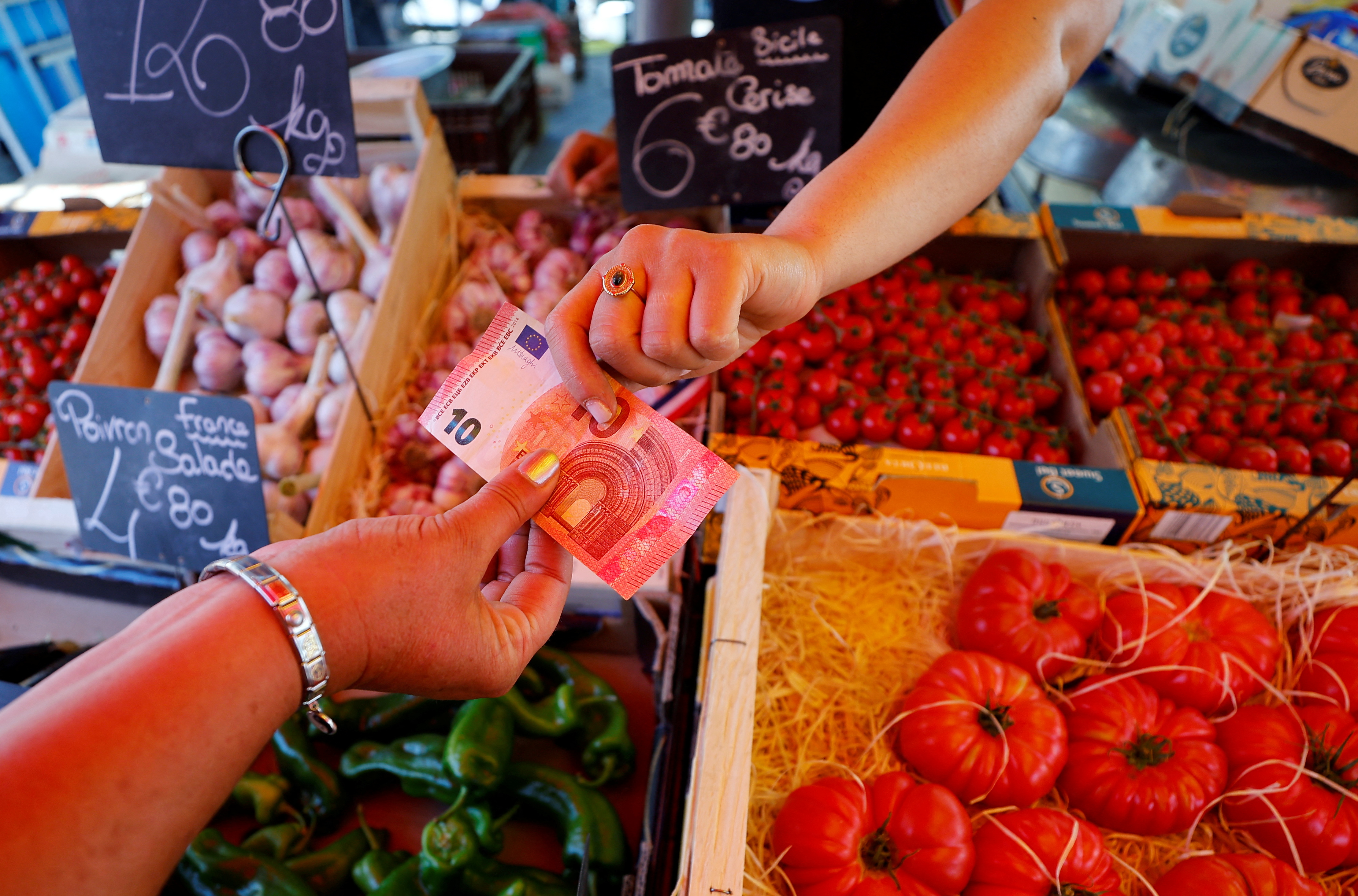 A shopper pays with a ten Euro bank note at a local market in Nice