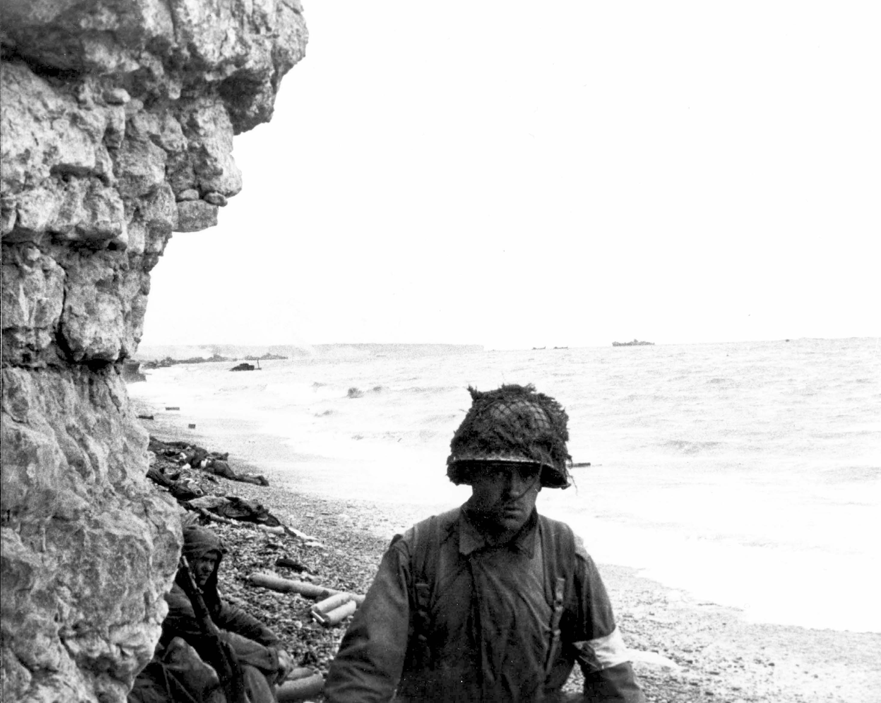 A U.S. Army medic moves along a narrow strip of Omaha Beach administering first aid to men wounded in the Normandy landing on D-Day
